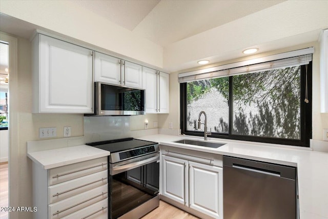 kitchen with white cabinets, sink, light stone countertops, and stainless steel appliances