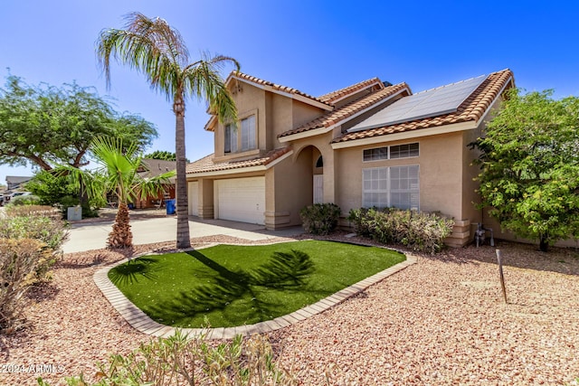 mediterranean / spanish-style home with a garage, driveway, roof mounted solar panels, and stucco siding