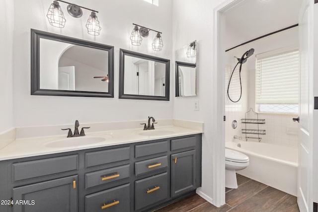 bathroom with a sink, double vanity, toilet, and wood finished floors