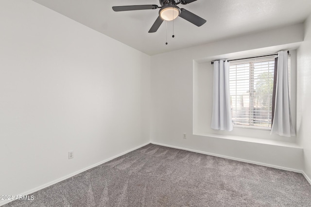 unfurnished room with baseboards, a ceiling fan, and dark carpet