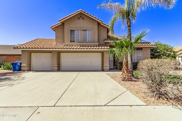 mediterranean / spanish-style house with a tiled roof, a garage, driveway, and stucco siding