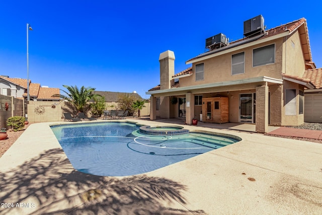 view of swimming pool with a patio, a fenced backyard, a pool with connected hot tub, and cooling unit