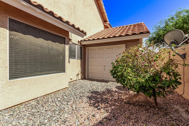 view of home's exterior with an attached garage, stucco siding, and a tile roof