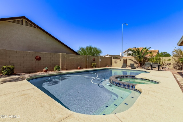 view of swimming pool with a patio, a fenced backyard, and a pool with connected hot tub