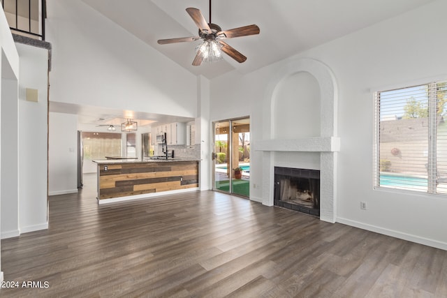 unfurnished living room featuring high vaulted ceiling, a large fireplace, dark hardwood / wood-style floors, and plenty of natural light