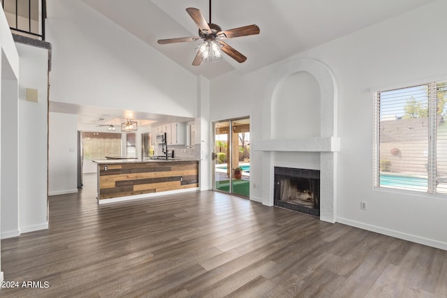 unfurnished living room featuring ceiling fan, dark wood finished floors, baseboards, and a fireplace