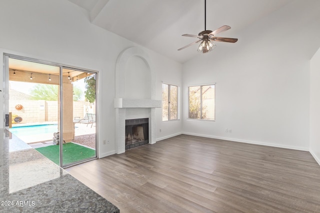 unfurnished living room with a fireplace, high vaulted ceiling, a ceiling fan, baseboards, and wood finished floors