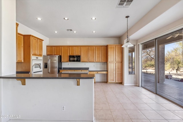 kitchen with pendant lighting, stainless steel fridge, sink, and a breakfast bar area