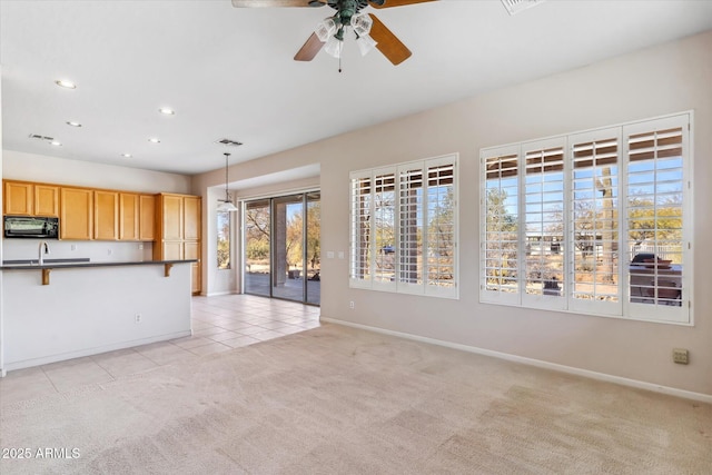 unfurnished living room featuring sink, light colored carpet, and ceiling fan