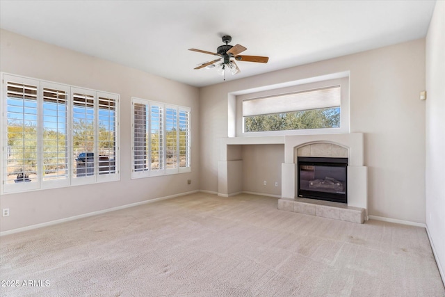 unfurnished living room featuring ceiling fan, light colored carpet, and a tiled fireplace