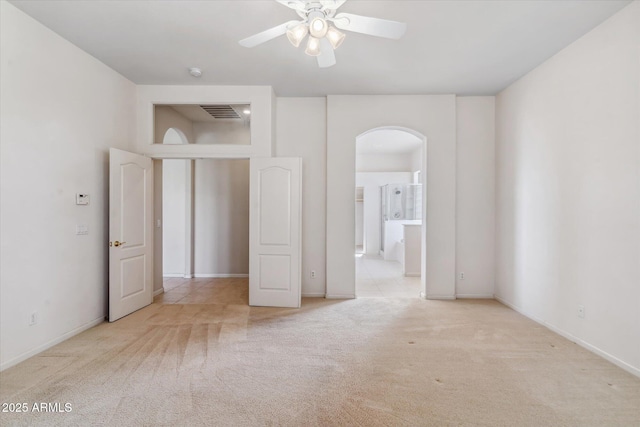 unfurnished bedroom with connected bathroom, light colored carpet, and ceiling fan