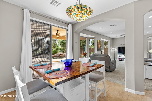 dining area with light carpet, arched walkways, visible vents, and ceiling fan