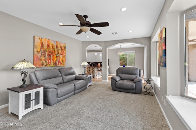 living area with visible vents, ceiling fan, arched walkways, and carpet