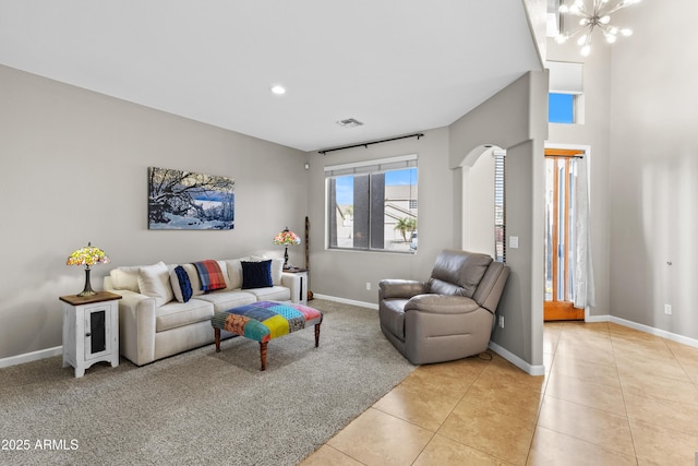 living room with a chandelier, arched walkways, light tile patterned flooring, and baseboards