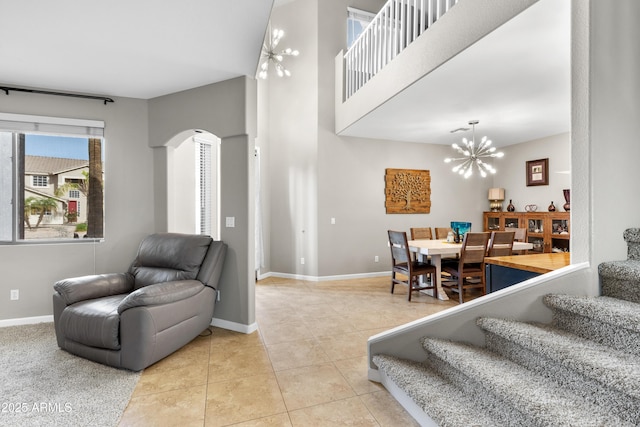 tiled living room featuring baseboards, arched walkways, a chandelier, and stairs