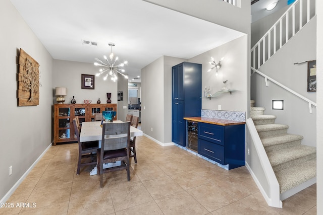 dining space with visible vents, baseboards, an inviting chandelier, stairway, and light tile patterned flooring