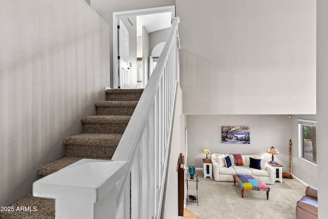 stairs featuring carpet flooring, a towering ceiling, and baseboards