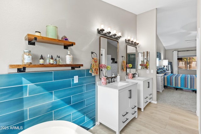 bathroom featuring a soaking tub, wood finished floors, and vanity