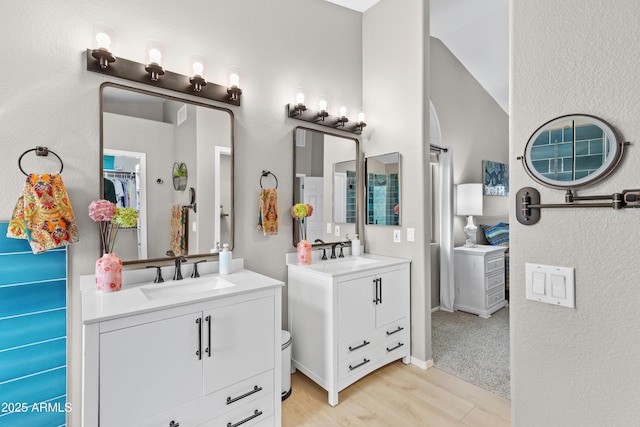 full bathroom with two vanities, a sink, and wood finished floors