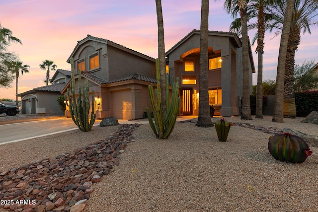 mediterranean / spanish home featuring driveway, stucco siding, and a tiled roof