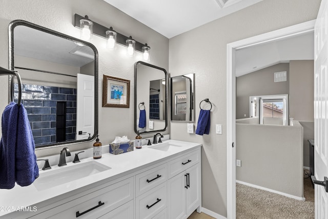 full bathroom featuring baseboards, double vanity, a sink, and vaulted ceiling
