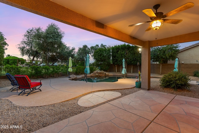 patio terrace at dusk with a fenced backyard and ceiling fan