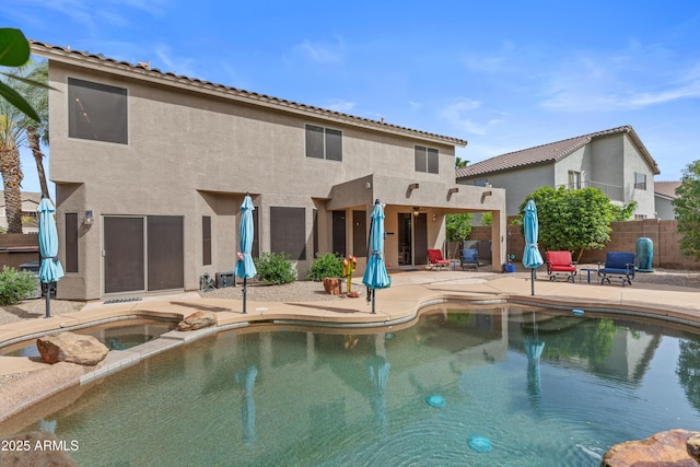view of swimming pool featuring a pool with connected hot tub, fence, and a patio
