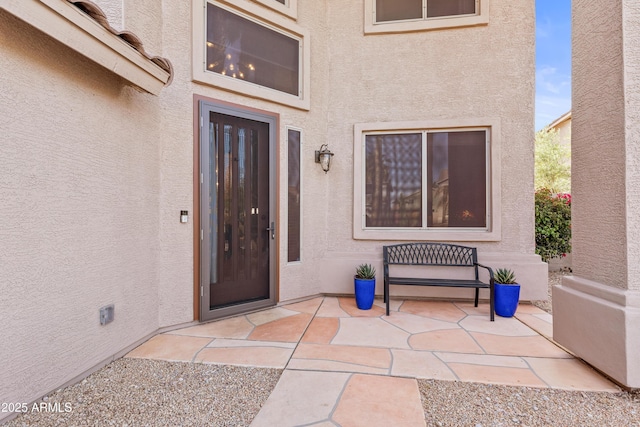property entrance with a patio and stucco siding