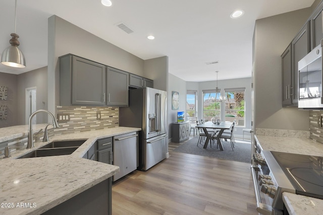 kitchen featuring decorative light fixtures, sink, gray cabinetry, decorative backsplash, and stainless steel appliances