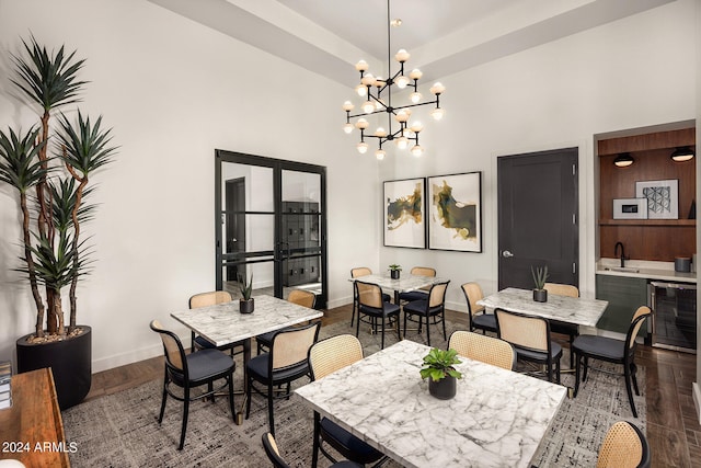 dining area with sink, wood-type flooring, beverage cooler, and an inviting chandelier