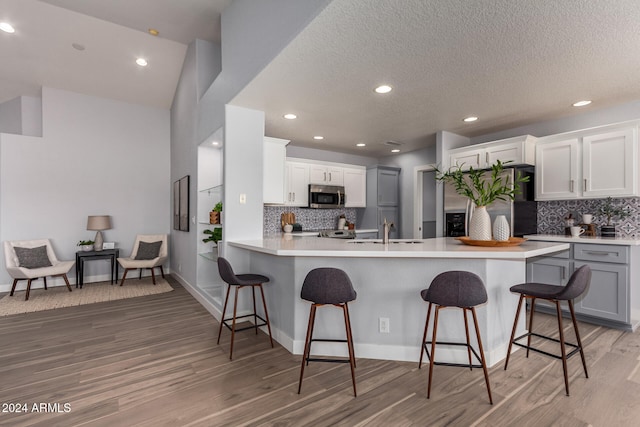 kitchen with gray cabinets, white cabinetry, hardwood / wood-style floors, and stainless steel appliances