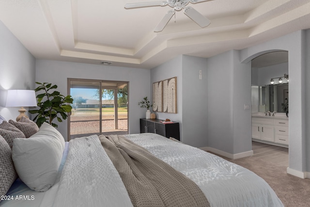 carpeted bedroom featuring ceiling fan, access to exterior, connected bathroom, and a tray ceiling