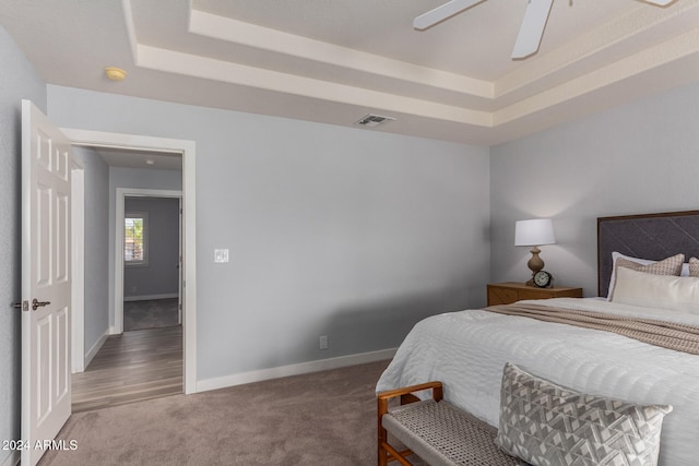 bedroom featuring a tray ceiling, carpet flooring, and ceiling fan