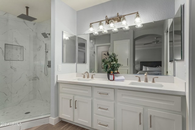 bathroom with a tile shower, vanity, hardwood / wood-style flooring, and ceiling fan