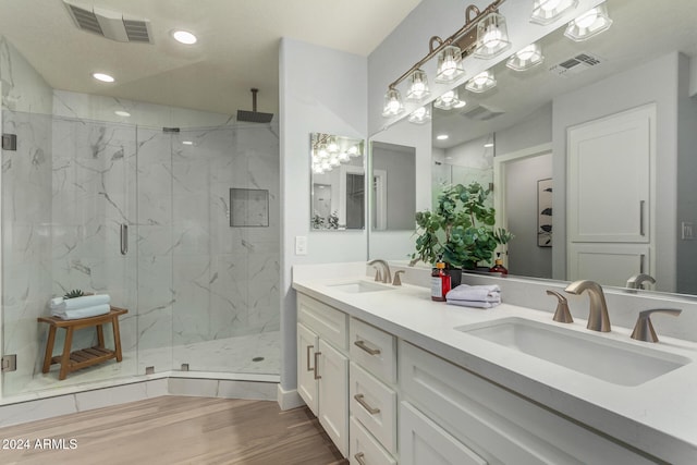 bathroom with hardwood / wood-style floors, a shower with door, and vanity