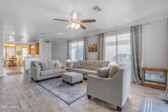 living room featuring ceiling fan, crown molding, and light wood-type flooring