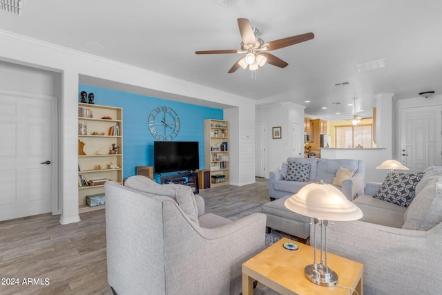 living room with crown molding, light hardwood / wood-style floors, and ceiling fan