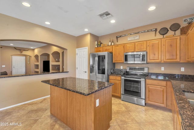 209 N 237th Ave, Buckeye, AZ 85396 - kitchen featuring stainless steel appliances, arched walkways, a kitchen island, light tile patterned flooring, and dark stone counters