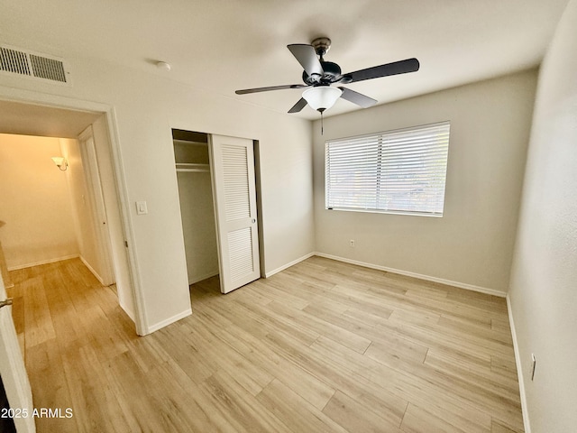 unfurnished bedroom featuring visible vents, baseboards, light wood finished floors, and a closet