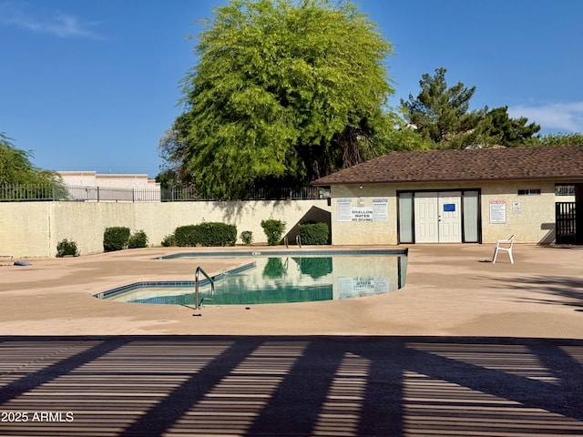 pool with a patio, a hot tub, and fence