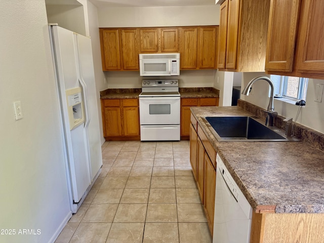 kitchen featuring brown cabinetry, white appliances, light tile patterned flooring, and a sink