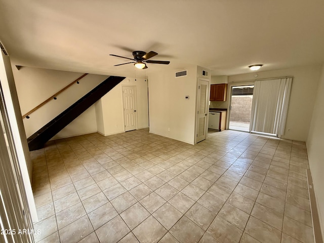 unfurnished living room with light tile patterned flooring, visible vents, ceiling fan, and stairs