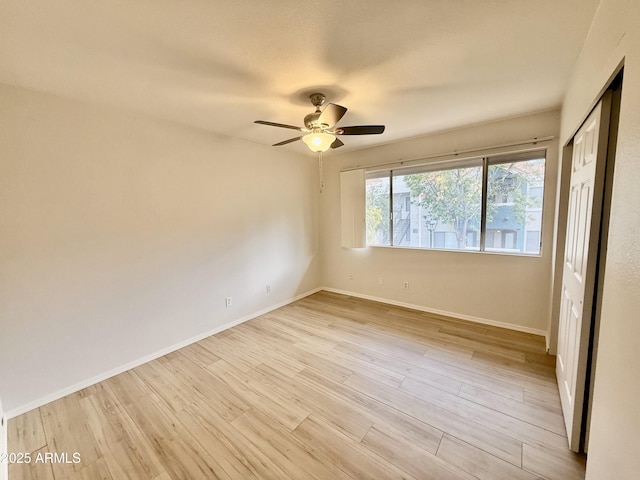 empty room with light wood-type flooring, a ceiling fan, and baseboards