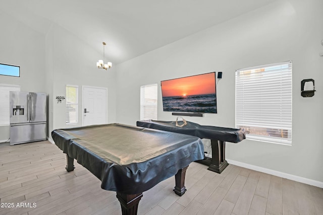 recreation room with baseboards, light wood-style floors, a chandelier, and high vaulted ceiling