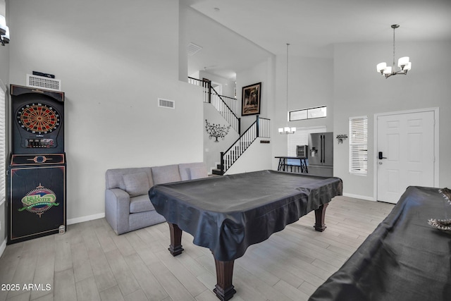 recreation room with light wood-style floors, a chandelier, baseboards, billiards, and a towering ceiling