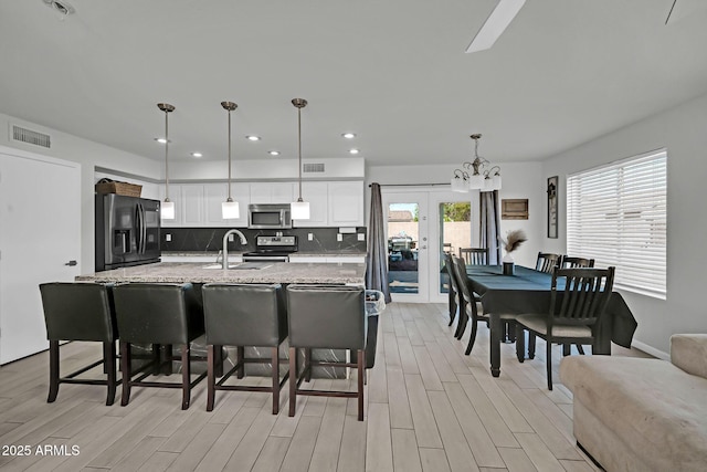kitchen featuring a sink, light wood-style floors, stainless steel appliances, and visible vents