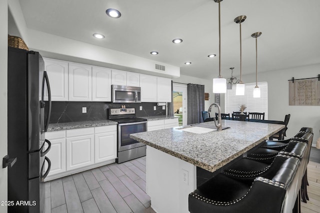 kitchen with a sink, appliances with stainless steel finishes, wood finish floors, and a kitchen breakfast bar