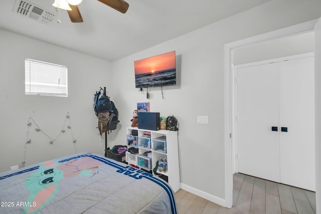 bedroom with a ceiling fan, baseboards, wood finished floors, visible vents, and a closet