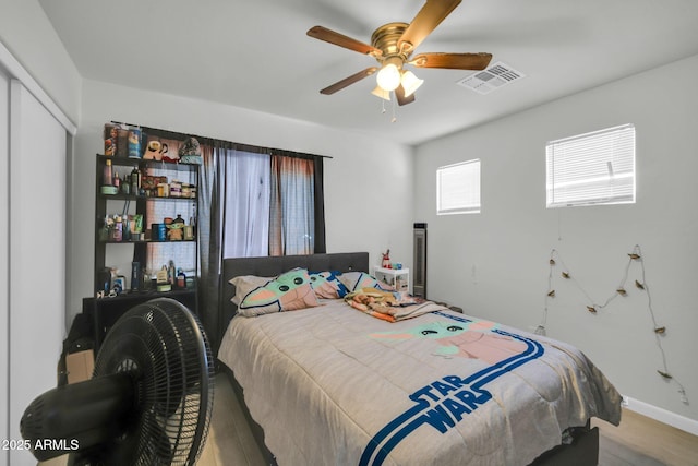 bedroom featuring a closet, a ceiling fan, wood finished floors, and visible vents