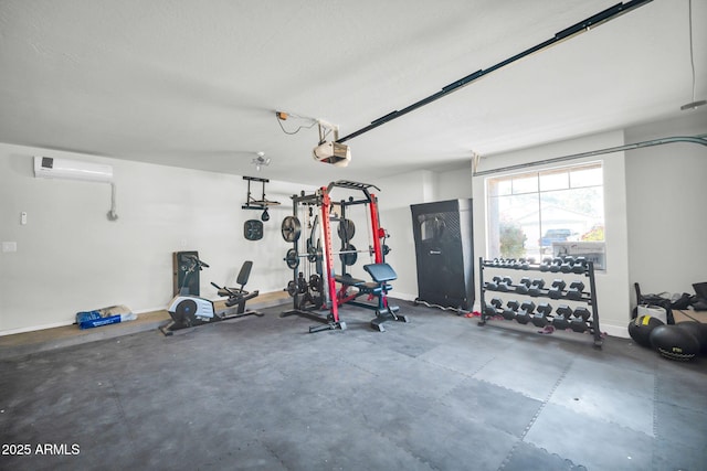 workout room with an AC wall unit, a garage, and baseboards